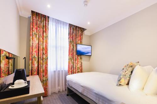 um quarto de hotel com uma cama e uma televisão em Byron Hotel em Londres