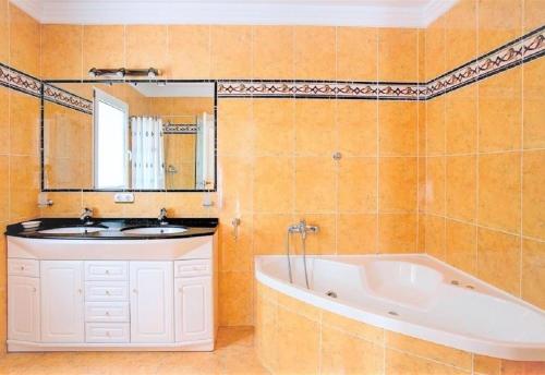 een badkamer met een wastafel, een bad en een spiegel bij Luxury Villa at La Sella Resort in Pedreguer
