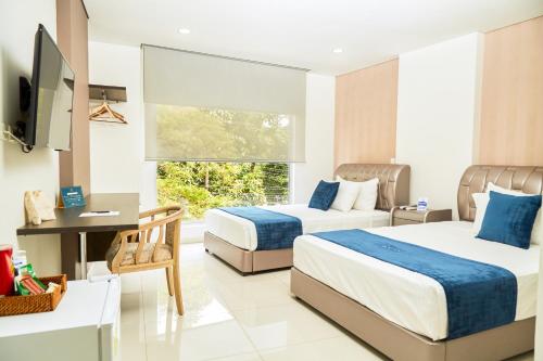 a hotel room with two beds and a television at Solev Hotel in Villavicencio