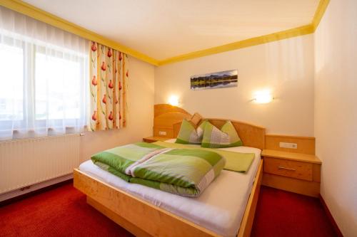 a bedroom with a bed with green sheets and a window at Val Monte in Kappl