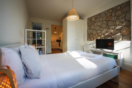a large white bed in a room with a tv at Solar Studio Fontainhas in Porto