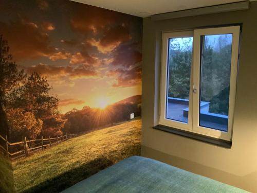 a bedroom with a window with a sunset mural on the wall at Auberge Sans Souci in Valkenburg
