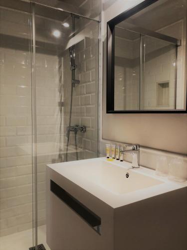 a bathroom with a sink and a glass shower at Hostal Hom Museo in Seville
