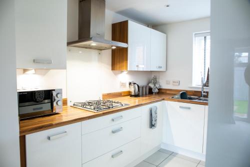 a kitchen with white cabinets and a stove top oven at Modern House with FREE Private Parking, WIFI & Netflix in Stratford-upon-Avon