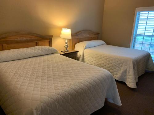 a bedroom with two beds and a lamp and a window at Carr's Northside Hotel and Cottages in Gatlinburg