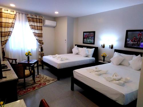 una camera d'albergo con due letti e una finestra di Venezia Suites Hotel Iloilo a Città di Iloilo