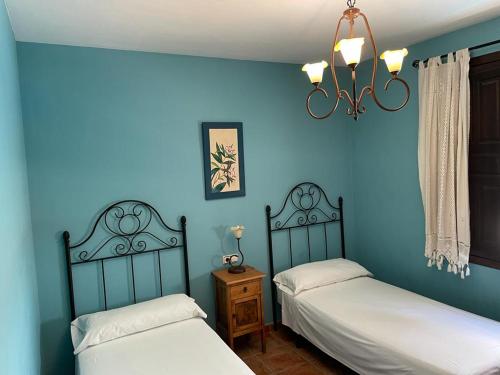 2 camas en una habitación con paredes azules en Casa Rural San Anton Cuenca, en El Provencio