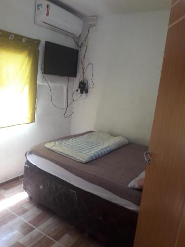 a small bedroom with a bed in a room with a window at Casitas na Praia in Barra de Santo Antônio