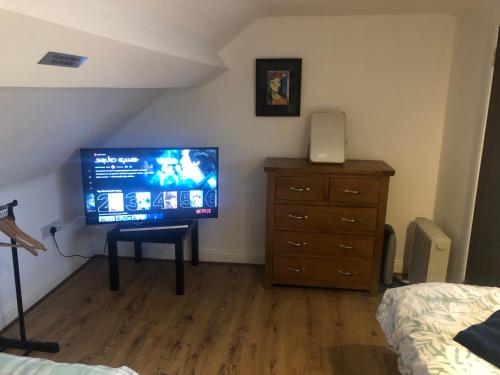 a bedroom with a television and a dresser with a bed at Central Lisburn Duplex Apartment No Parties in Lisburn