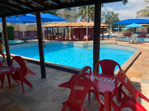 uma piscina com cadeiras vermelhas e uma mesa e uma mesa e cadeiras em Suíte 1015 - Thermas Place com Parque Aquático em Caldas Novas