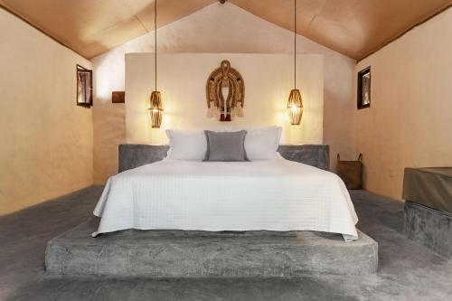 a bedroom with a bed with white sheets and lights at Ventos Morere Hotel & Beach Club in Ilha de Boipeba