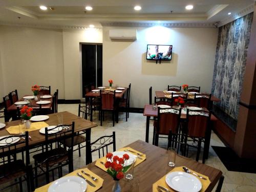 a dining room with tables and chairs and a tv at Venezia Suites Hotel Iloilo in Iloilo City