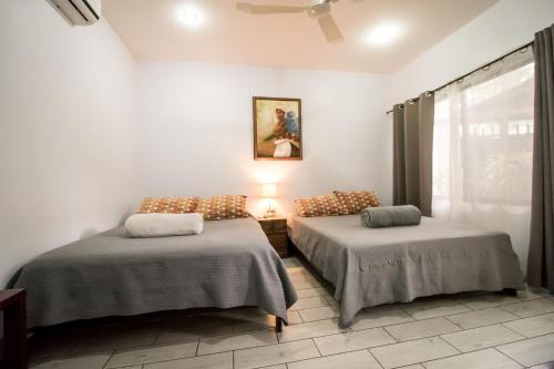1 dormitorio con 2 camas y ventana en Terida Airport B&B, en Alajuela