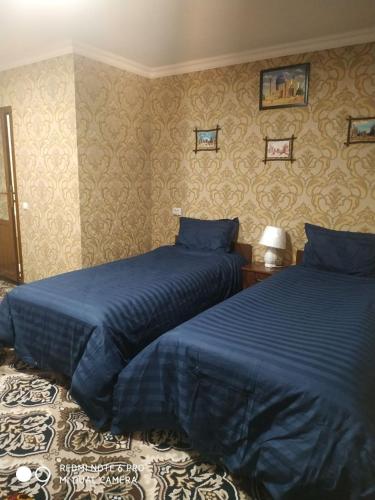 two beds in a bedroom with blue sheets at Imran&Bek in Samarkand