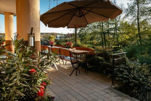 a patio with an umbrella and a table and chairs at Wypoczynek u Piotra z jacuzzi in Susiec
