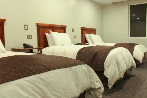a hotel room with three beds and a window at Hotel Unu in Huancayo