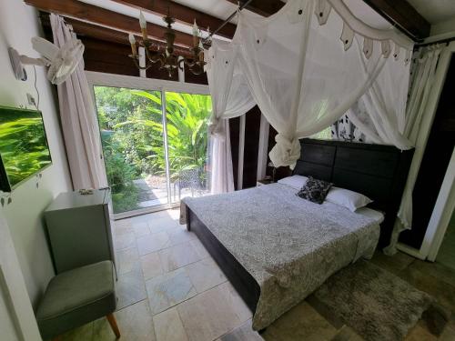 a bedroom with a bed and a large window at Racoon Lodge in Pointe-à-Pitre