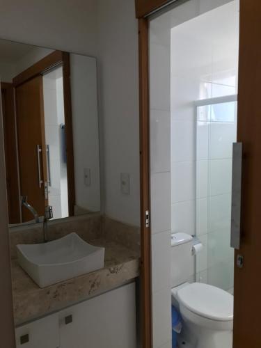 ein Badezimmer mit einem Waschbecken, einem WC und einem Spiegel in der Unterkunft Vista Mar Premium in Ilhéus