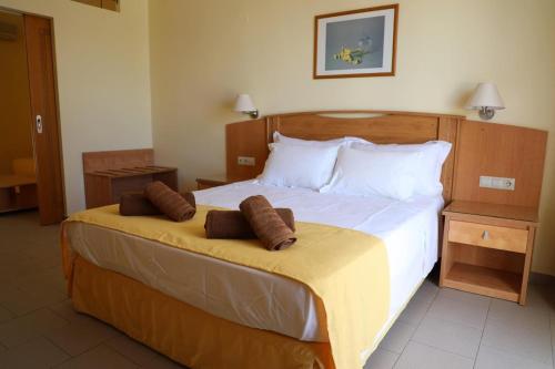a bedroom with a large bed with two pillows on it at Coloma Apartments Pefkos in Pefki