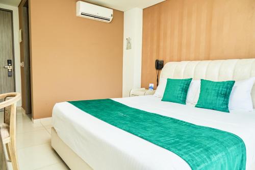 a hotel room with a large bed with green pillows at Solev Hotel in Villavicencio