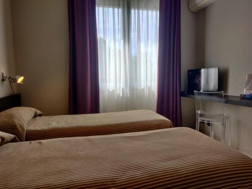 a hotel room with two beds and a window with purple curtains at Hotel San Francesco in Borgomanero