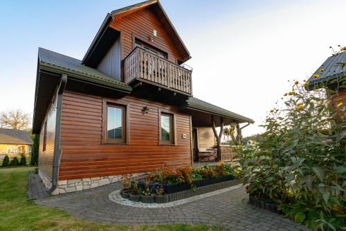 uma casa de madeira com uma varanda em cima em Domek Majowy em Susiec