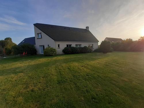 a white house on a grass field with the sun behind it at Les grandes Masures B&B in Varengeville-sur-Mer