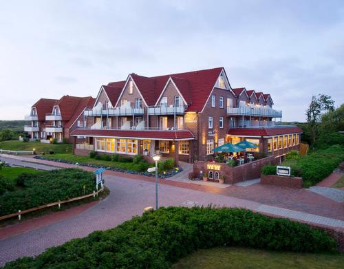 a large building with a building with lights on at Hotel Strandhof in Baltrum