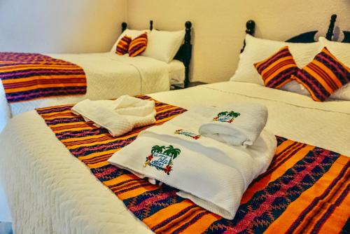 two beds with towels on them in a room at La Isla Resort in Caye Caulker