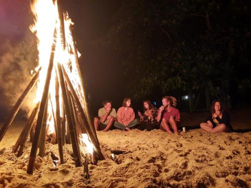 a group of people sitting around a bonfire on the beach at Hostel Trópico de Capricórnio - Tenório in Ubatuba