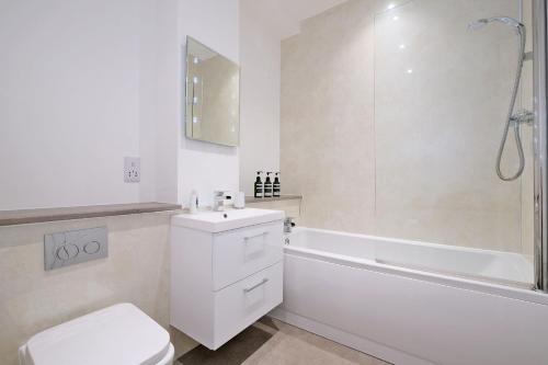 a white bathroom with a toilet and a bath tub at 5* Luxury 1 Bedroom Apartment in City Centre in Aberdeen