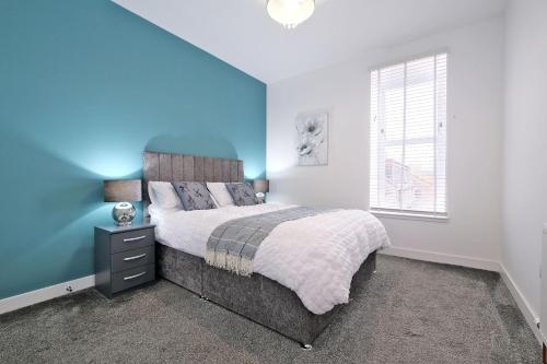 a bedroom with a bed and a blue wall at 5* Luxury 1 Bedroom Apartment in City Centre in Aberdeen