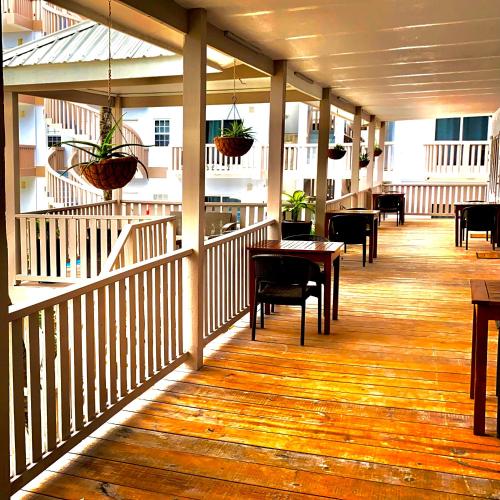 a porch with tables and chairs and potted plants at La Isla Resort in Caye Caulker