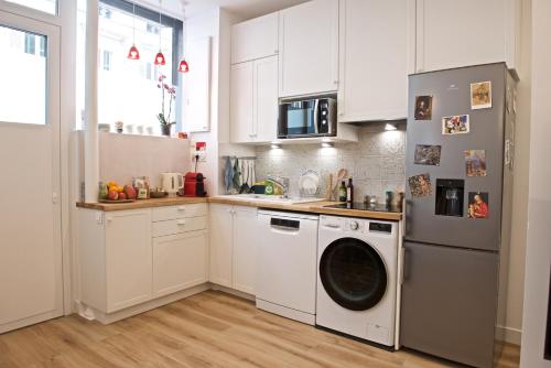 a kitchen with white cabinets and a washing machine at CHARMING Parisian Apartment WITH AIR CONDITIONING - CLIMATISATION & 2 BEDROOMS - Batignolles PARIS in Paris