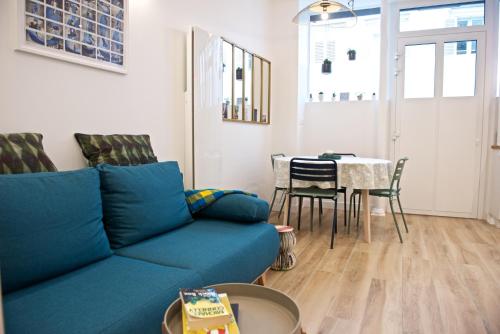 a living room with a blue couch and a table at CHARMING Parisian Apartment WITH AIR CONDITIONING - CLIMATISATION & 2 BEDROOMS - Batignolles PARIS in Paris