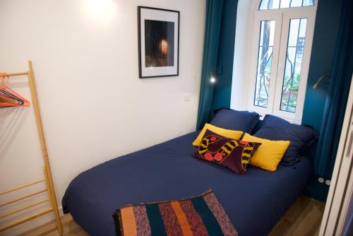 um quarto com uma cama azul com almofadas em CHARMING Parisian Apartment WITH AIR CONDITIONING - CLIMATISATION & 2 BEDROOMS - Batignolles PARIS em Paris