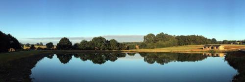 a view of a lake with a house in the background at Cambridgeshire Lakes - luxury lodges in a stunning lake location in Gamlingay