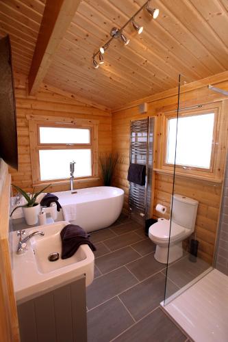 a bathroom with a tub and a toilet and a sink at Cambridgeshire Lakes - luxury lodges in a stunning lake location in Gamlingay