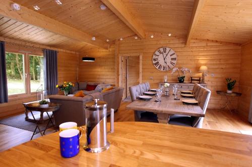 a living room with a table and a clock on the wall at Cambridgeshire Lakes - luxury lodges in a stunning lake location in Gamlingay