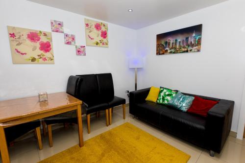 a living room with a black couch and a table at Comfortable Stays - Shirley, Solihull in Birmingham