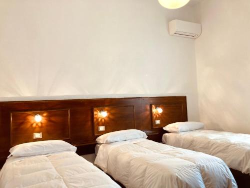 two beds in a room with white sheets at Hotel Livio in Brescia