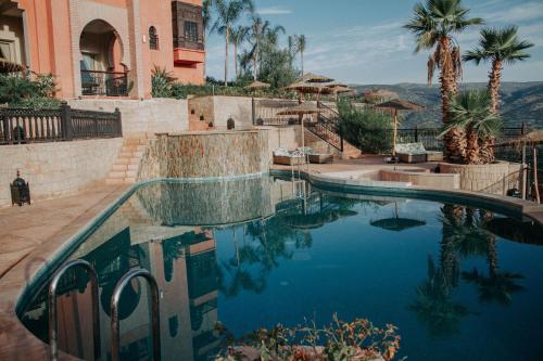 a swimming pool in front of a house with palm trees at Borj Des Cascades & Spa in Ouzoud