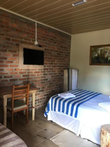 1 dormitorio con cama y pared de ladrillo en POUSADA DAS PIPAS, en Vacaria