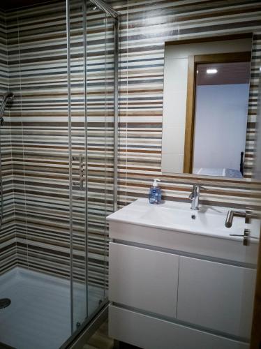 a bathroom with a sink and a shower and a mirror at Casa dos Trenós in Sabugueiro