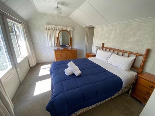 a bedroom with a large blue bed and a mirror at Garden Cottage - Lake Tekapo in Lake Tekapo