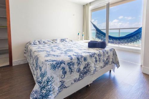sypialnia z niebiesko-białym łóżkiem i oknem w obiekcie Luxo na beira mar de Porto Mirim RN por Carpediem w mieście Jacumã