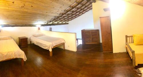 a bedroom with two beds and a wooden floor at Casa Bromélia Green in Itacaré