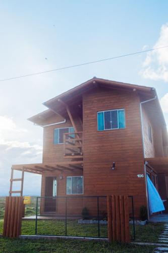 a wooden house with a wrap around porch at Recanto do Mar in Balneário Gaivotas