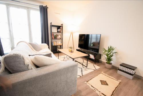 a living room with a couch and a television at Joli studio tout confort à 2 pas de la gare Poissy in Poissy