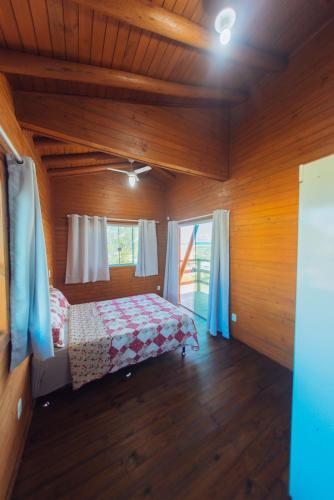 a bedroom with a bed in a wooden room at Recanto do Mar in Balneário Gaivotas